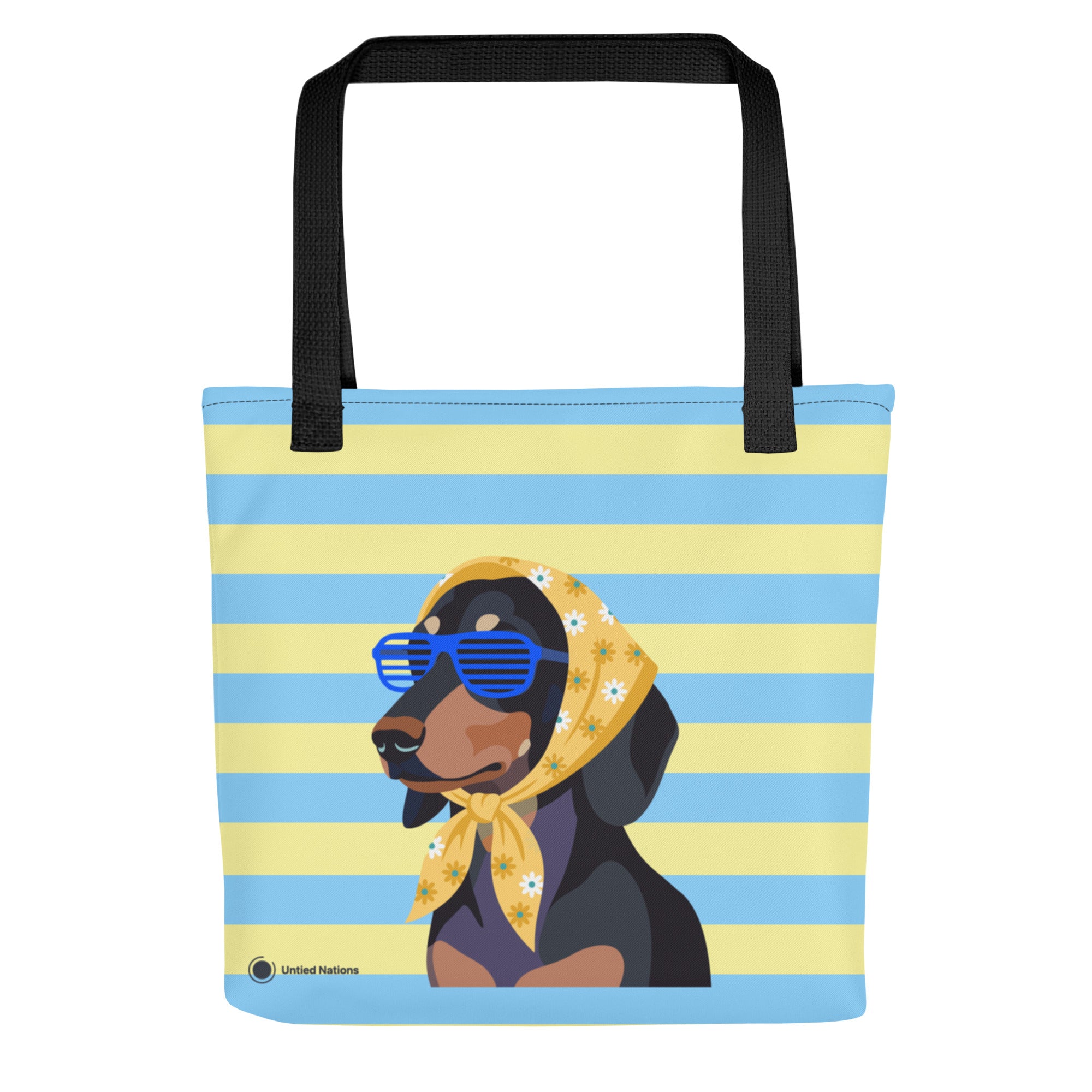 A tote bag with black handles, featuring a graphic of a black and tan dog wearing blue sunglasses and a yellow floral bandana, set against a light blue and pale yellow striped background. The brand name 'Untied Nations' is printed in the bottom left corner.