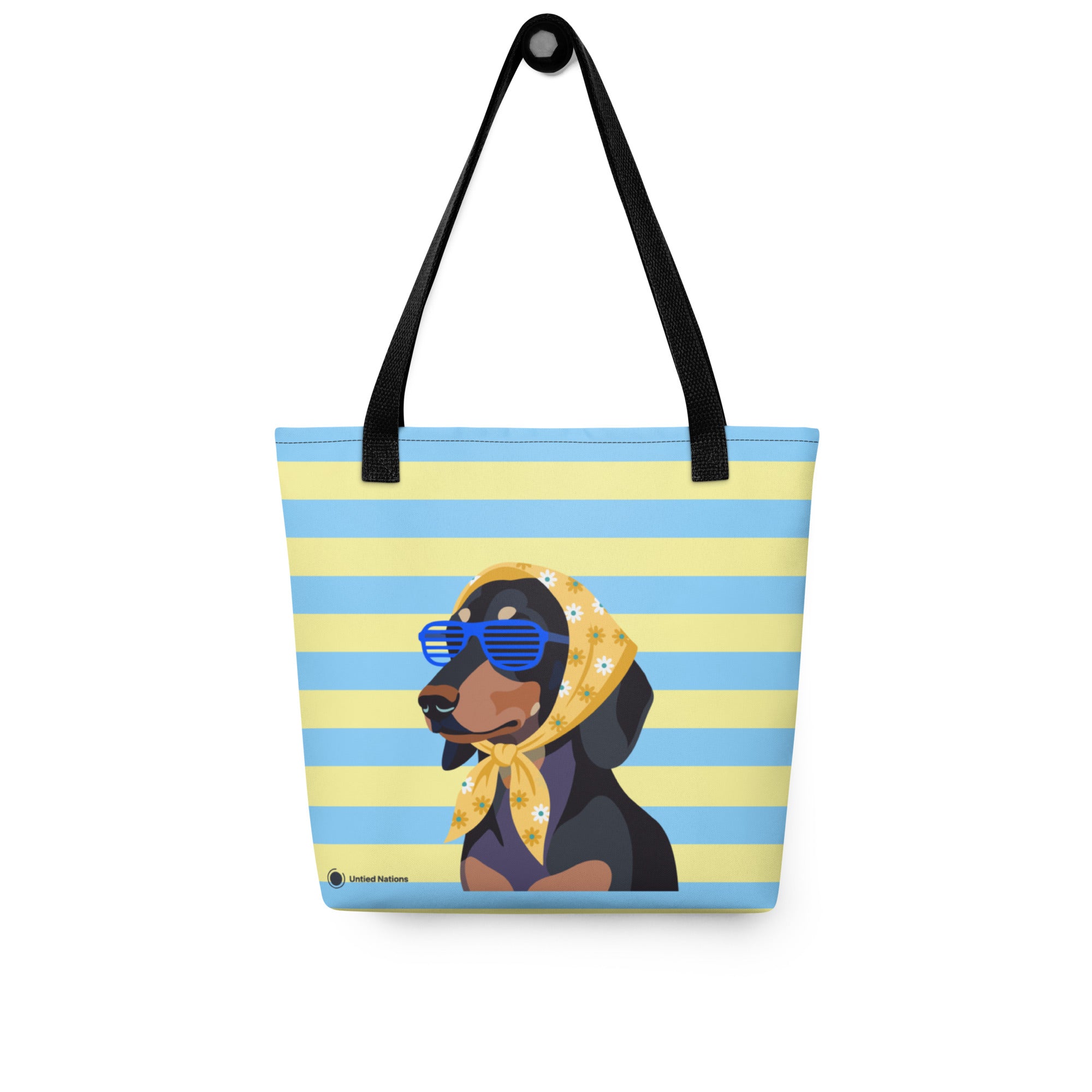 A tote bag with a blue and yellow striped background featuring a cartoon Rottweiler dog wearing blue sunglasses and a yellow bandana. The bag has black shoulder straps and a small 'Untied Nations' brand label near the bottom left.