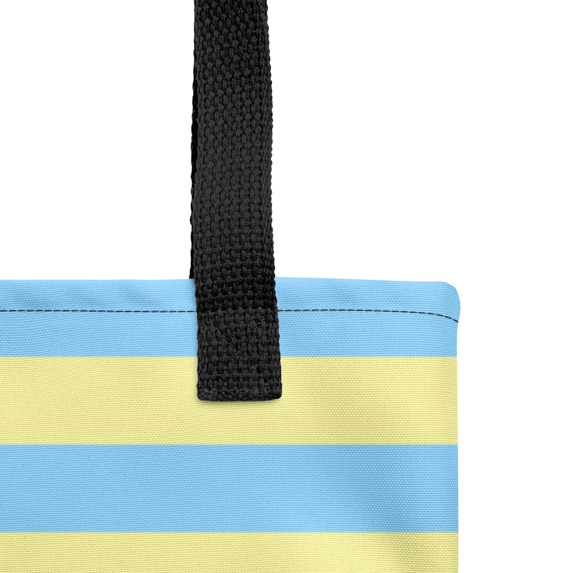 Close-up of a striped tote bag with horizontal light blue and pale yellow bands and a black woven handle, shown on a white background.