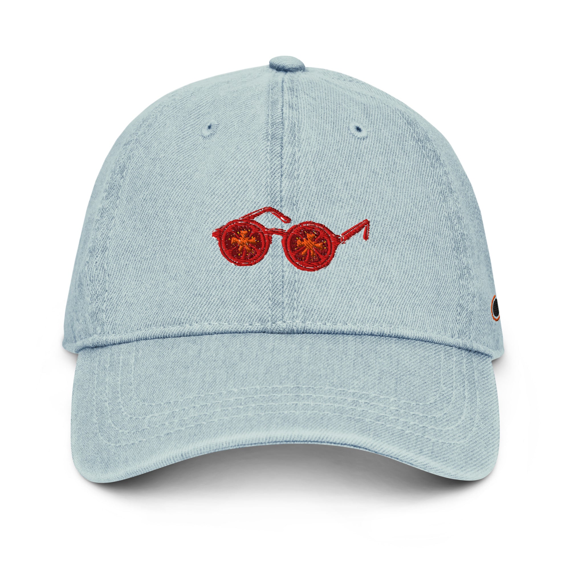 A light blue denim baseball cap featuring an embroidered pair of tomatosunglasses on the front, set against a plain white background.