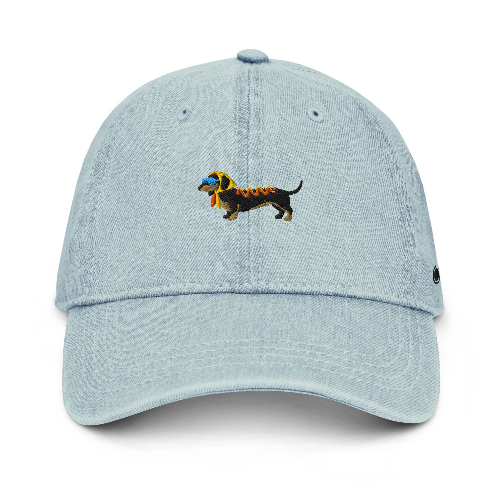 A light blue denim baseball cap featuring an embroidered dachshund dog on the front. The dog is black with a yellow headscarf, a pair of light blue sunglasses, and ketchup and mustard on its back.