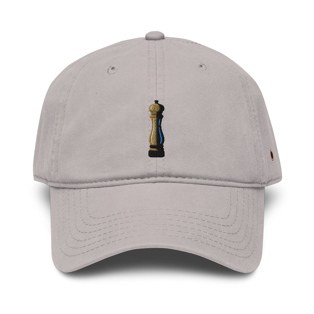 A light gray dad hat baseball cap featuring a small embroidered pepper grinder graphic on the front and a small orange embroidered logo on the side, set against a plain white background.