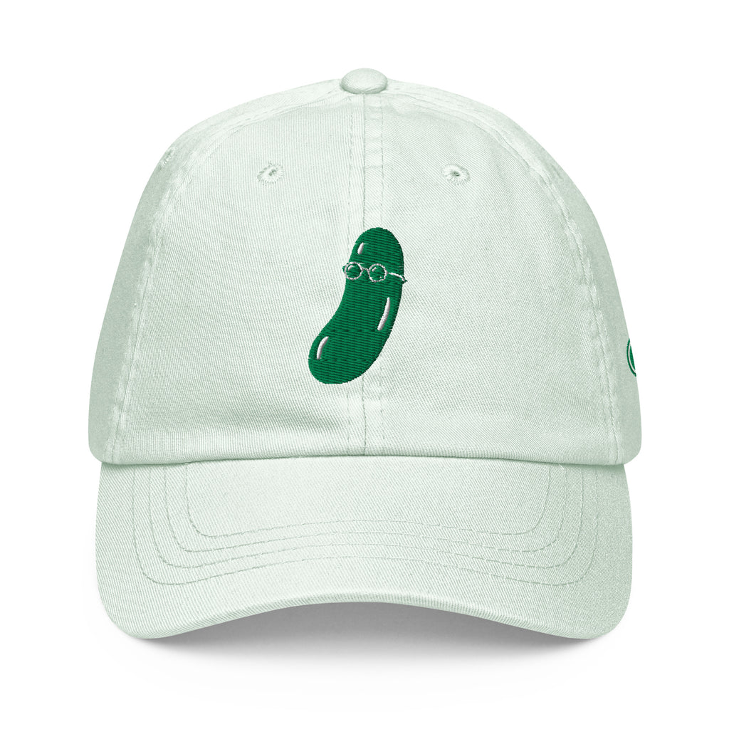 A light mint green cotton baseball cap featuring a dark green embroidered cucumber wearing round glasses on the front, set against a plain white background.