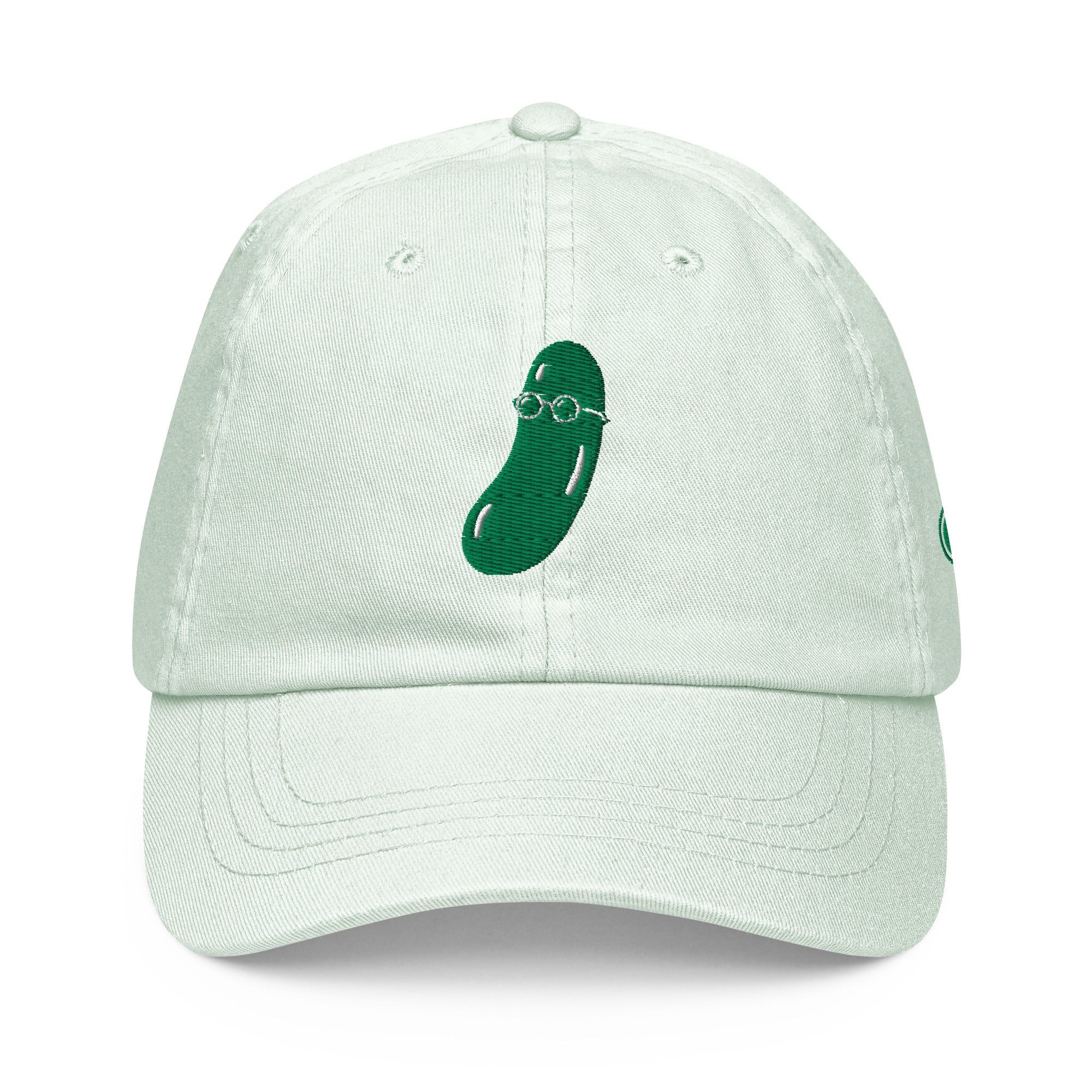A light mint green cotton baseball cap featuring a dark green embroidered cucumber wearing round glasses on the front, set against a plain white background.