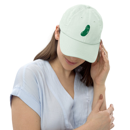 Woman wearing a light green cap with embroidered cucumber on a white background