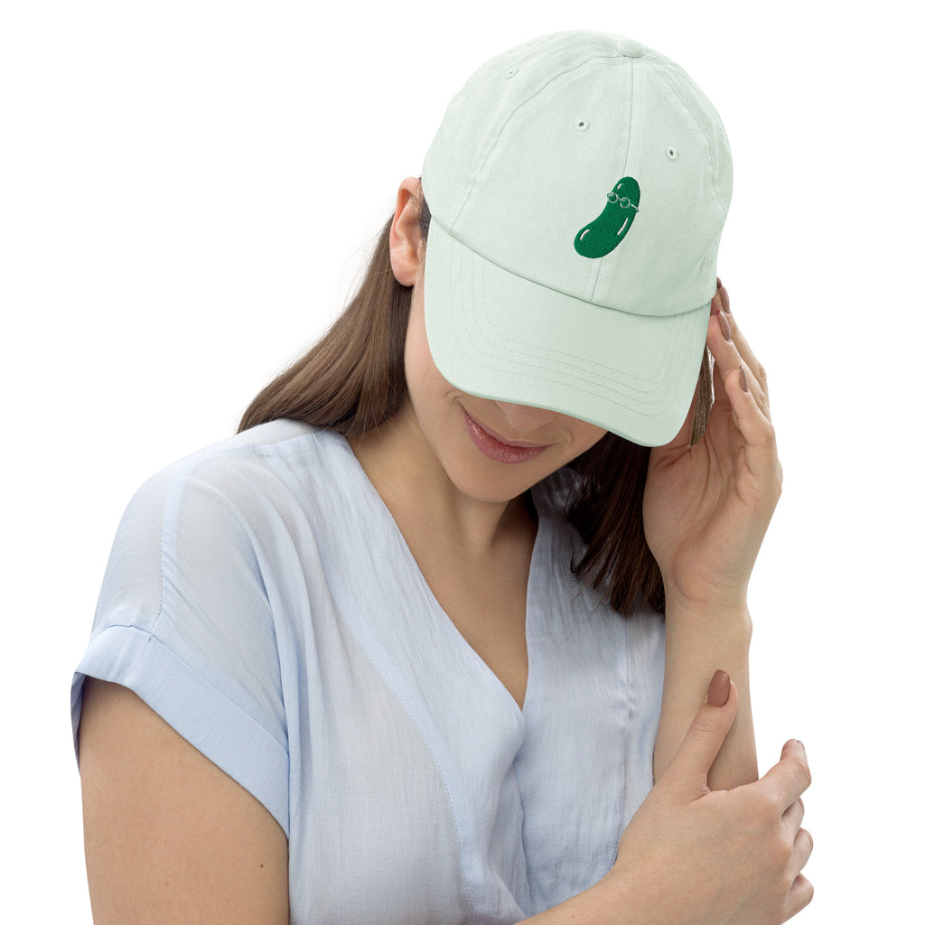 Woman wearing a mint green cap with embroidered cucumber on a white background