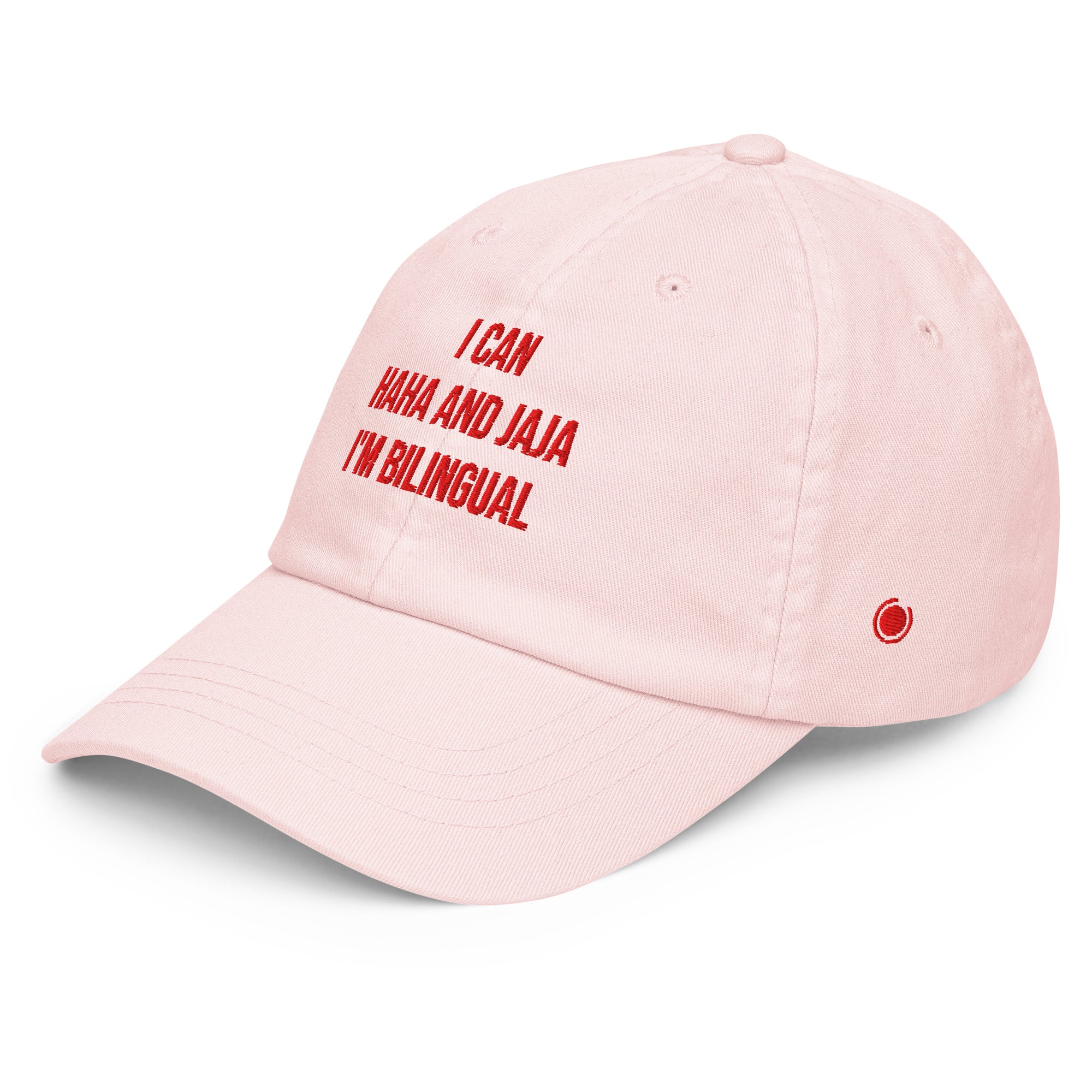 A light pink baseball cap with red embroidered text reading 'I CAN HAH AND JAJA I'M BILINGUAL' on the front, shown on a clean white background.