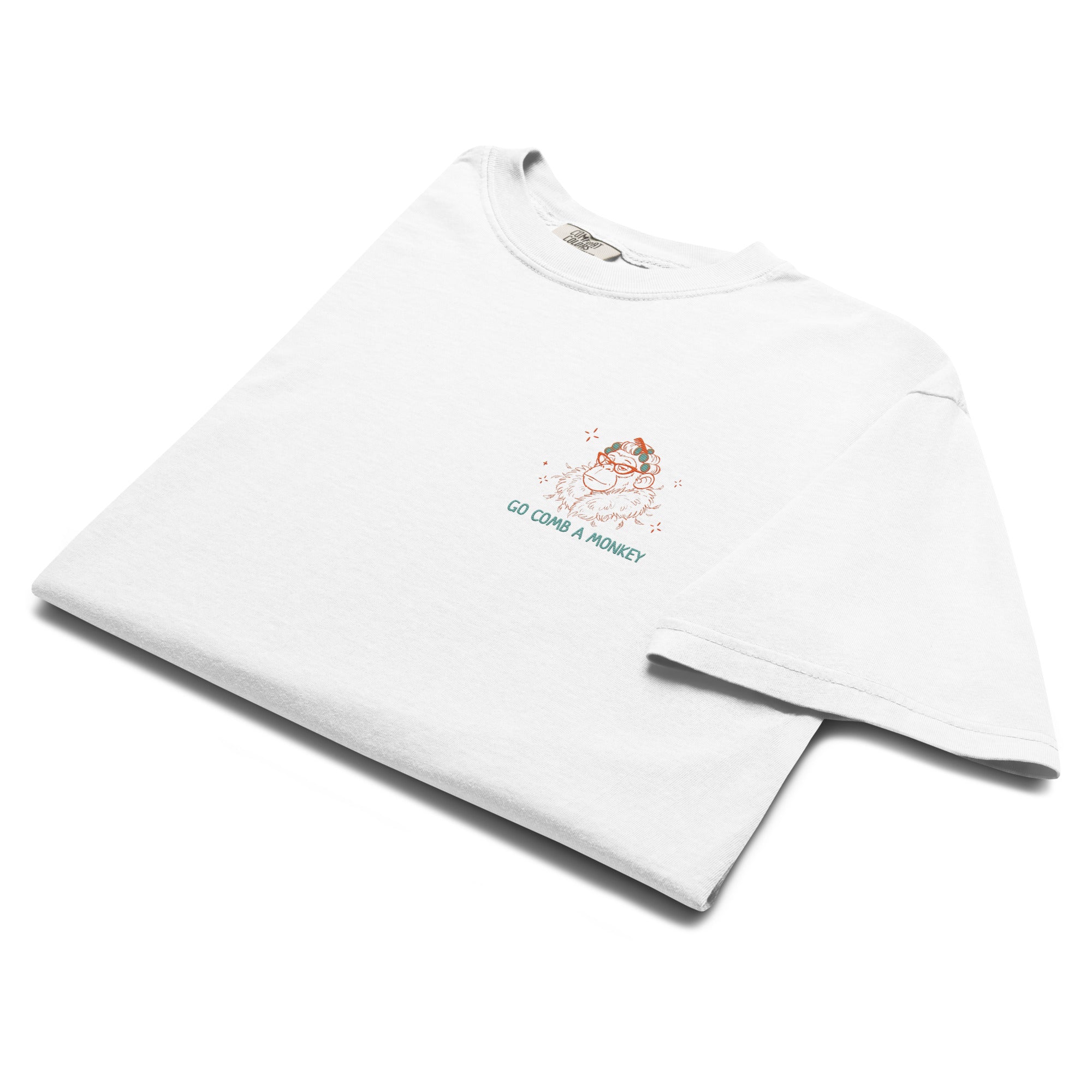 A folded white short-sleeve t-shirt with a small graphic on the left chest showing a cartoon monkey and the text 'GO COMB A MONKEY' in teal and orange, displayed on a clean white background.