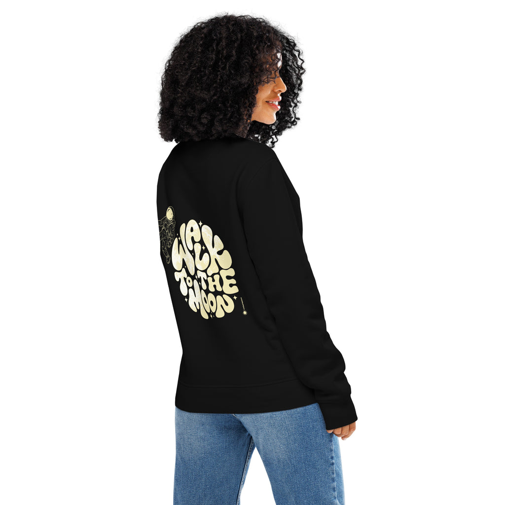 A woman with curly black hair is shown from the back wearing a black sweatshirt with a large cream-colored graphic on the back that reads 'Walk to the moon.' She is also wearing blue jeans, set against a plain white background.