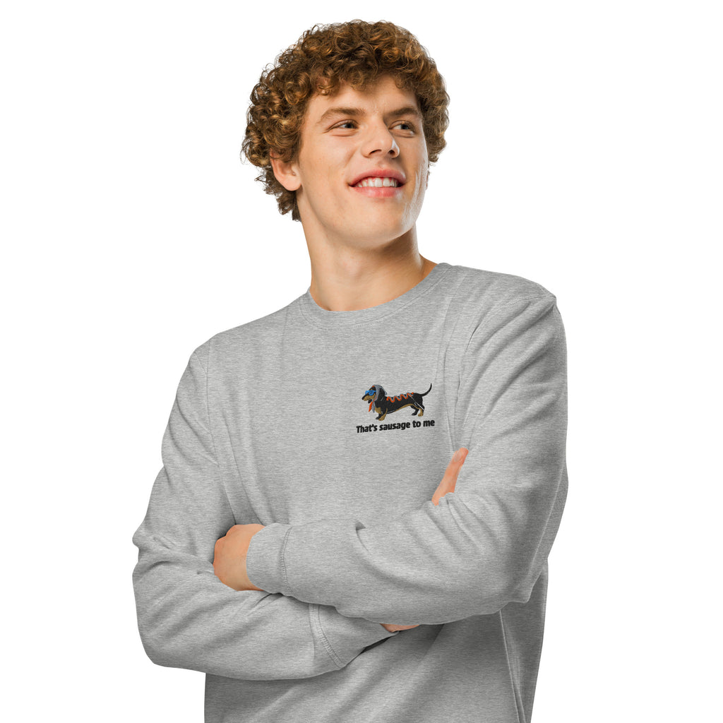 A smiling young man with curly brown hair wearing a light gray crewneck sweatshirt, posed with arms crossed against a solid white background.