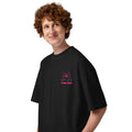 A person wearing a black oversized graphic tshirt with a pink spider wearing roller skates and the text "I believe I spider" printed on the left chest