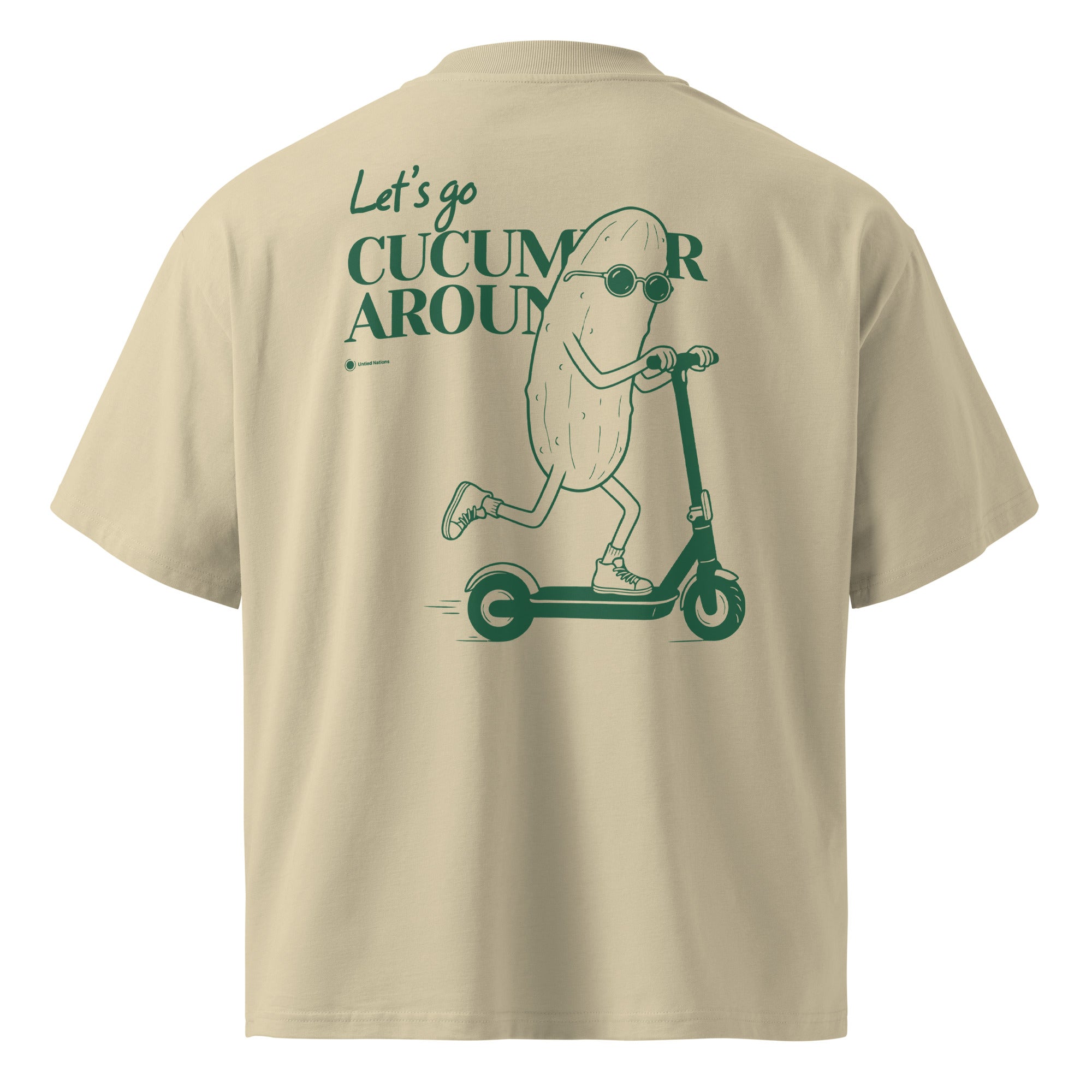 A beige short-sleeve t-shirt shown from the back, featuring a dark green graphic of a cartoon cucumber character wearing sunglasses and riding a scooter, with the text 'Let's go CUCUMBER AROUND'.