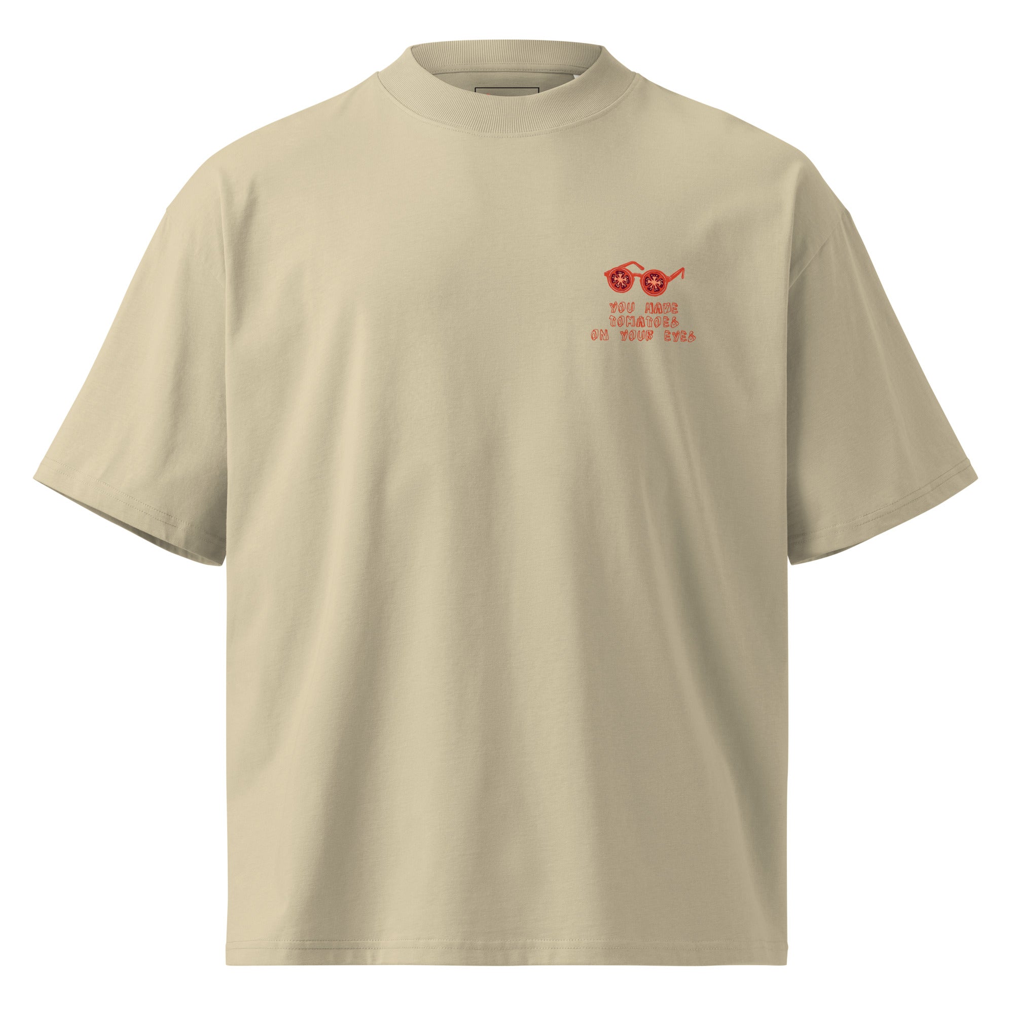 A beige short-sleeve crewneck t-shirt with a small red graphic on the left chest depicting sunglasses and the text 'YOU HAVE TOMATOES ON YOUR EYES'.