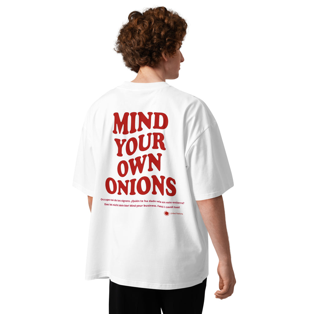A person shown from the back wearing an oversized white T-shirt with large red text reading “MIND YOUR OWN ONIONS” across the back, photographed against a clean white studio background.