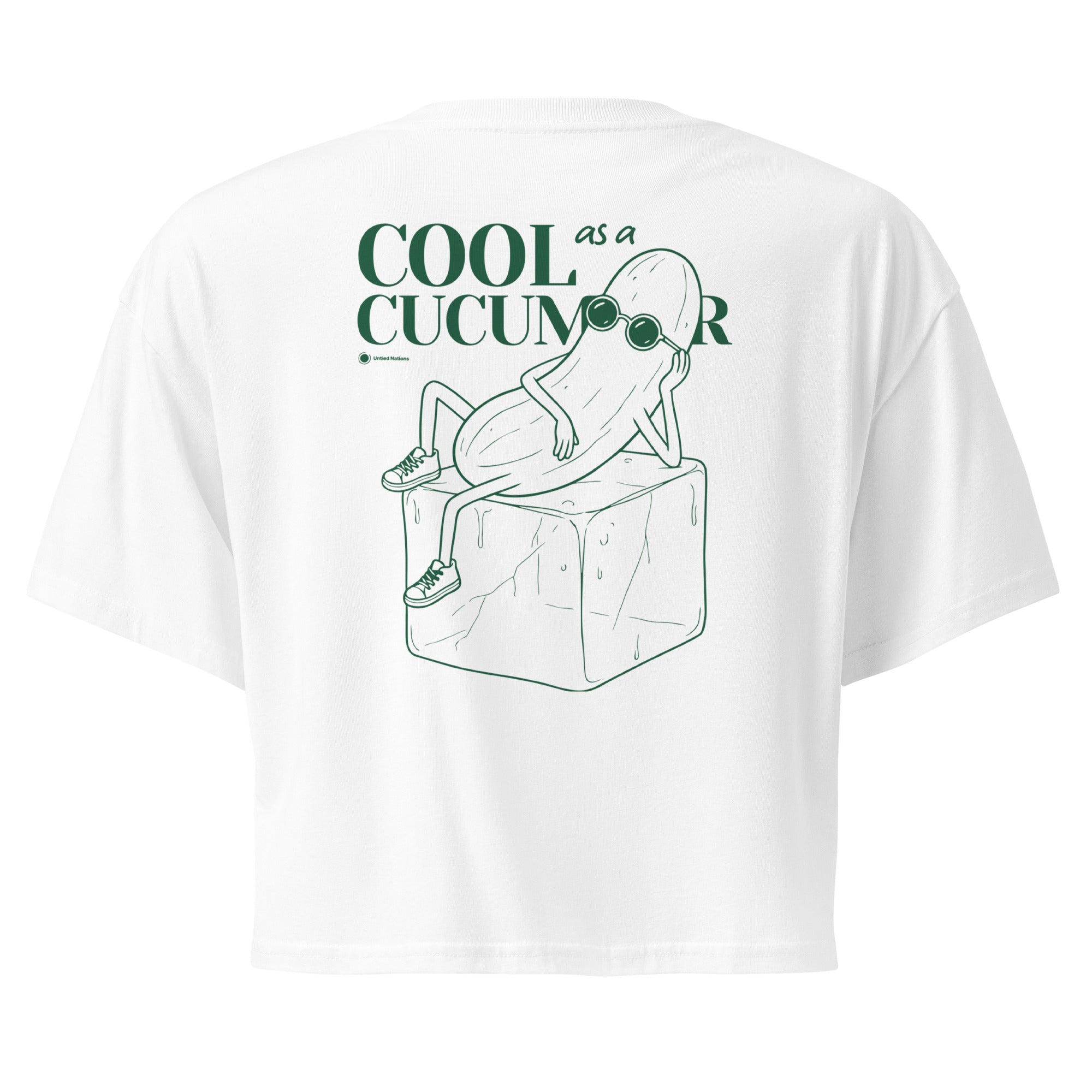 White short-sleeve crop top shown from the back, featuring a green line art graphic of a cucumber character wearing sunglasses and sitting on an ice cube, with the text 'COOL as a CUCUMBER'.