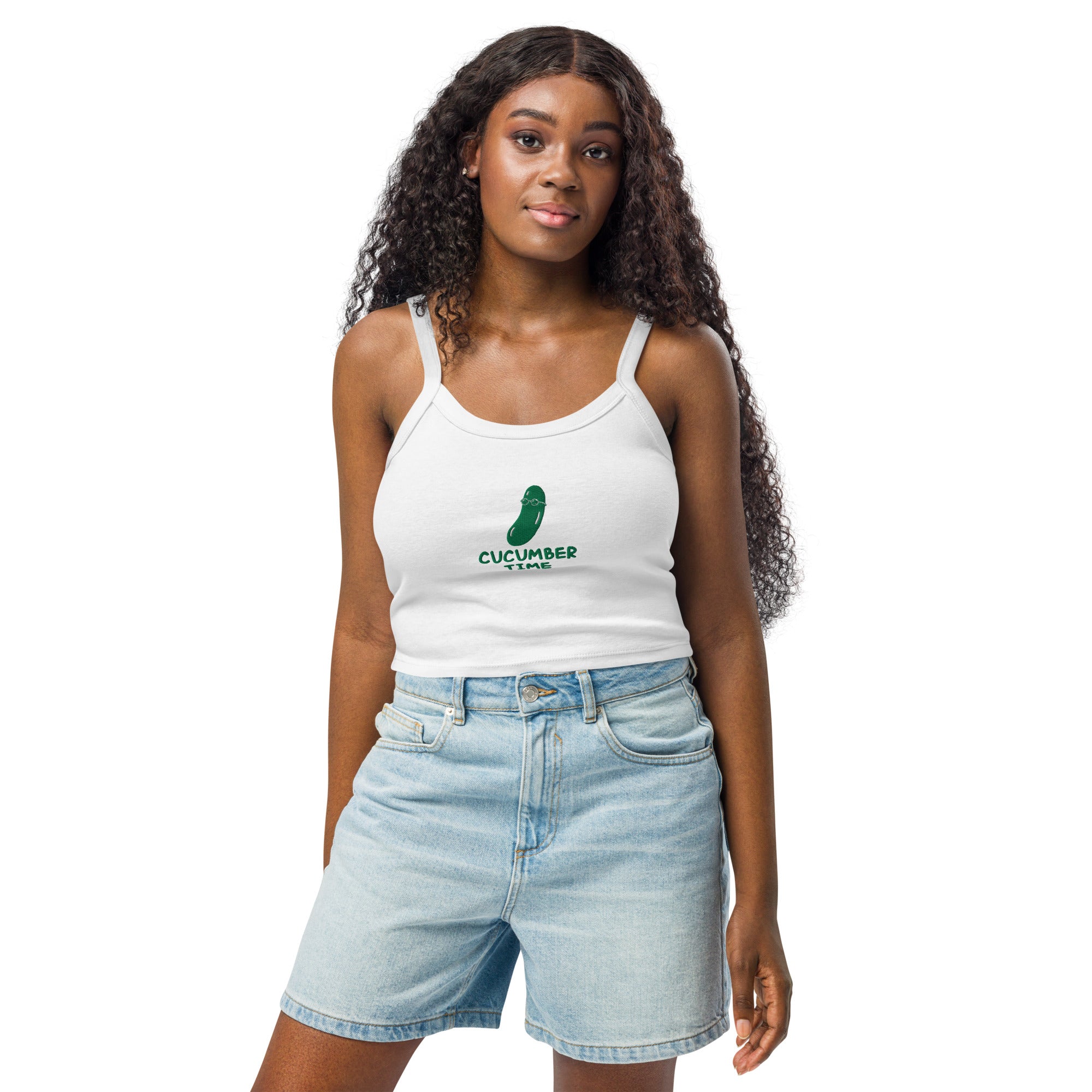 Woman wearing a white tank top with a green logo and denim shorts on a white background